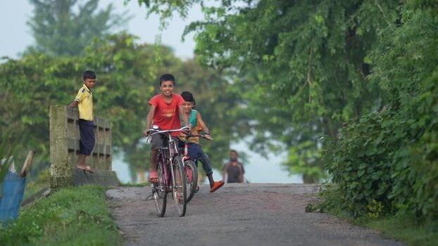 View of children riding bicycles on a rural road Bangladesh. View of children riding bicycles on a rural road Bangladesh.