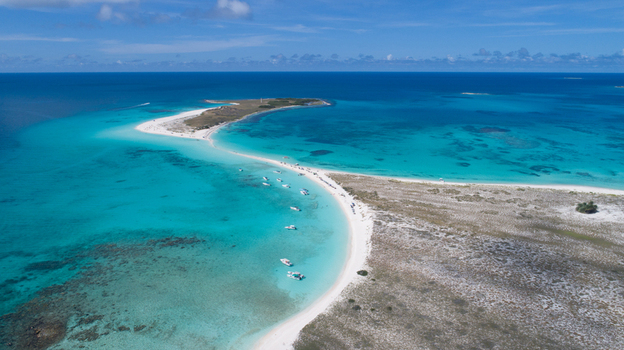 Aerial view of Los Roques archipelago featuring turquoise waters white sandbars and small boats anchored along the coastline in Los Roques Dependencias Federales Venezuela. Aerial view of Los Roques archipelago featuring turquoise waters white sandbars and small boats anchored along the coastline in Los Roques Dependencias Federales Venezuela.