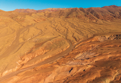 Aerial view of the arid desert landscape with undulating sand dunes and rugged mountain ridges under a clear blue sky in San Pedro de Atacama Antofagasta Chile. Aerial view of the arid desert landscape with undulating sand dunes and rugged mountain ridges under a clear blue sky in San Pedro de Atacama Antofagasta Chile.