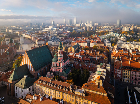 Aerial view of the historic old town with red rooftops and church spires under a morning mist with the modern city skyline in the background in Warsaw Poland. Aerial view of the historic old town with red rooftops and church spires under a morning mist with the modern city skyline in the background in Warsaw Poland.