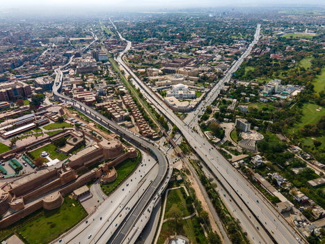 Aerial view of the historic Bala Hisar Fort surrounded by urban sprawl highways and green spaces in Peshawar Khyber Pakhtunkhwa Pakistan.
