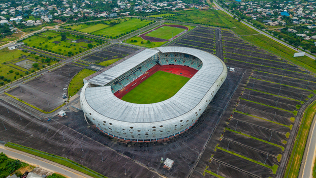 Aerial view of Godswill Akpabio Stadium with green pitch red running track and white roof surrounded by large parking lots and green landscapes in Uyo Akwa Ibom Nigeria. Aerial view of Godswill Akpabio Stadium with green pitch red running track and white roof surrounded by large parking lots and green landscapes in Uyo Akwa Ibom Nigeria.