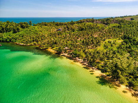 Aerial view of turquoise waters meet the sandy shore beneath a canopy of lush green trees painting a vivid tropical paradise Preah Sihanouk Sihanoukville Cambodia.
