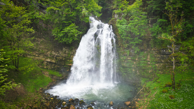Aerial view of Cascades du Flumen waterfall cascading down rocky cliffs surrounded by lush green forest in Septmoncel Les Molunes Bourgogne Franche Comte France. Aerial view of Cascades du Flumen waterfall cascading down rocky cliffs surrounded by lush green forest in Septmoncel Les Molunes Bourgogne Franche Comte France.