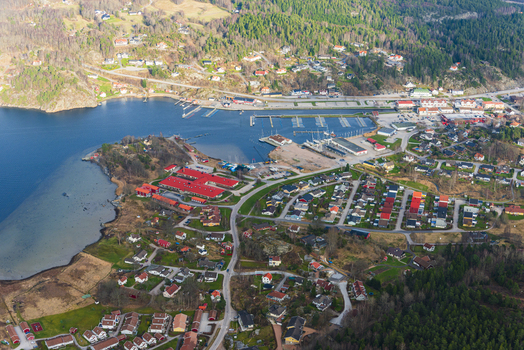 Aerial view of the coastal town featuring a marina with docked boats residential houses with colorful rooftops and surrounding forests along the bay in Henan Vastra Gotaland County Sweden. Aerial view of the coastal town featuring a marina with docked boats residential houses with colorful rooftops and surrounding forests along the bay in Henan Vastra Gotaland County Sweden.