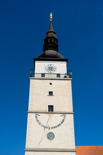 View of the historic City Tower featuring a clock face and sundial under a clear blue sky in Trnava Trnava Region Slovakia. View of the historic City Tower featuring a clock face and sundial under a clear blue sky in Trnava Trnava Region Slovakia.