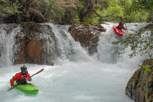 View of kayakers navigating the white water rapids of the Rio Manso waterfall surrounded by lush forest San Carlos de Bariloche Rio Negro Argentina. View of kayakers navigating the white water rapids of the Rio Manso waterfall surrounded by lush forest San Carlos de Bariloche Rio Negro Argentina.