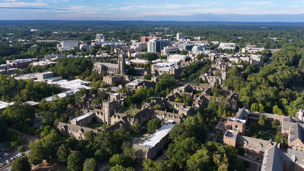 Aerial view of Duke University campus featuring the iconic Gothic architecture of the Duke Chapel surrounded by lush green trees and academic buildings in Durham North Carolina United States.