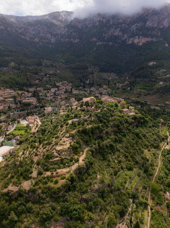 Aerial view of the historic village of Valldemossa with its stone buildings nestled among lush green hills and the Tramuntana mountains in Valldemossa Balearic Islands Spain.