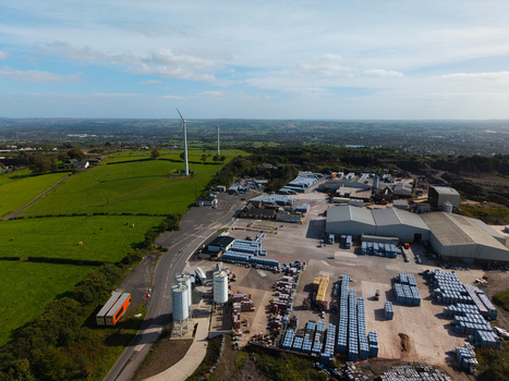 Aerial view of an industrial facility featuring warehouses storage silos and wind turbines situated amidst green fields in Lisburn Northern Ireland United Kingdom. Aerial view of an industrial facility featuring warehouses storage silos and wind turbines situated amidst green fields in Lisburn Northern Ireland United Kingdom.
