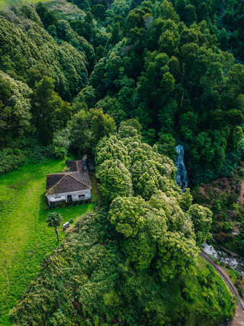Aerial view of a solitary house nestled amidst vibrant green hills and lush forests creating a serene contrast of nature and architecture Achada Açores Portugal. Aerial view of a solitary house nestled amidst vibrant green hills and lush forests creating a serene contrast of nature and architecture Achada Açores Portugal.