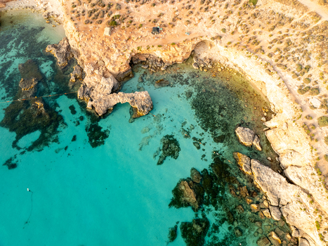 Aerial view of turquoise waters meet rugged cliffs in a mesmerizing dance of light and shadow at Blue Lagoon Comino Malta. Aerial view of turquoise waters meet rugged cliffs in a mesmerizing dance of light and shadow at Blue Lagoon Comino Malta.