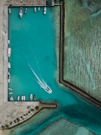 Aerial view of boats docked in the marina contrasting with the turquoise waters meeting the sandy shorelines Vashafaru Island Maldives.