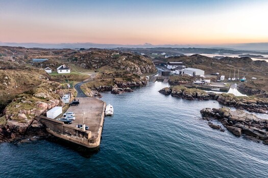Aerial view of the harbor and pier at Cloughglass with parked cars small boats and rugged rocky coastline under soft sunset light in Cloughglass County Donegal Ireland. Aerial view of the harbor and pier at Cloughglass with parked cars small boats and rugged rocky coastline under soft sunset light in Cloughglass County Donegal Ireland.