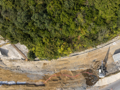 Aerial view of a construction site with an excavator working on a dirt road next to a dense forest in Istanbul Istanbul Turkiye.