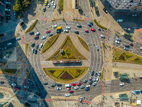 Aerial view of a busy urban roundabout with multiple lanes of traffic and a red tram in Poland. Aerial view of a busy urban roundabout with multiple lanes of traffic and a red tram in Poland.