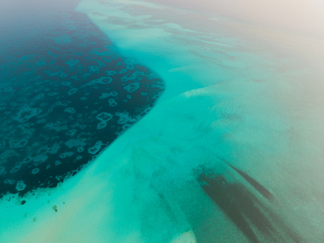 Aerial view of turquoise waters meeting the deep blue sea a tranquil contrast of hues near Kan island eagle ray Dhidhdhoo Thiladhunmathi Atoll Maldives.