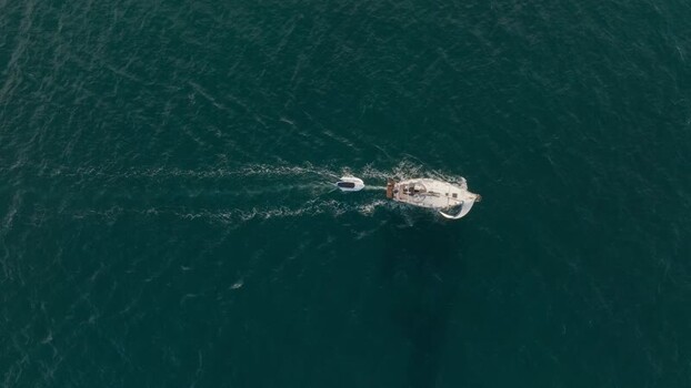 Aerial view of a sailboat towing a dinghy in Syracuse Italy. Aerial view of a sailboat towing a dinghy in Syracuse Italy.