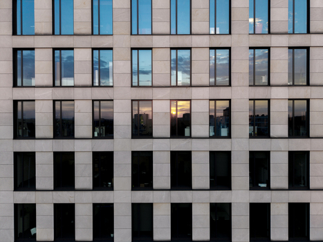 Aerial view of the modern stone facade of a building with grid like windows reflecting the sunset sky Krakow Lesser Poland Voivode Poland. Aerial view of the modern stone facade of a building with grid like windows reflecting the sunset sky Krakow Lesser Poland Voivode Poland.