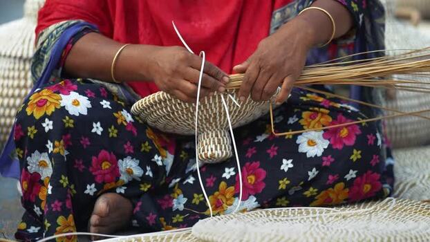 View of a woman weaving traditional baskets in Bogura Bangladesh. View of a woman weaving traditional baskets in Bogura Bangladesh.