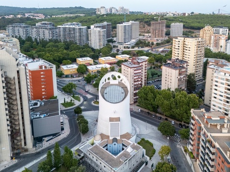 Alges Portugal 25 July 2026 Aerial view of the Santissima Trindade Church surrounded by modern residential buildings lush green trees and urban roads.