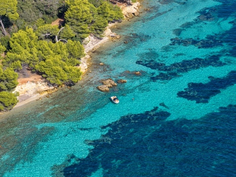 Aerial view of Ile Sainte Marguerite featuring turquoise waters rocky coastline lush pine trees and a small boat anchored near the shore in Cannes Provence Alpes Cote d Azur France. Aerial view of Ile Sainte Marguerite featuring turquoise waters rocky coastline lush pine trees and a small boat anchored near the shore in Cannes Provence Alpes Cote d Azur France.
