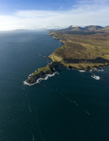 Aerial view of The Brother s Point peninsula jutting into the blue sea with rugged cliffs and distant mountains in Culnacnoc Scotland United Kingdom. Aerial view of The Brother s Point peninsula jutting into the blue sea with rugged cliffs and distant mountains in Culnacnoc Scotland United Kingdom.