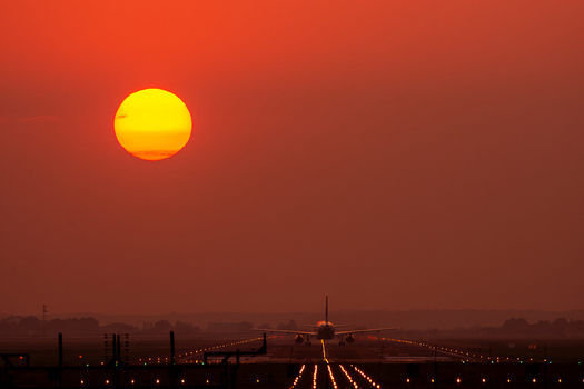 View of an airplane taxiing on the runway at Bucharest Henri Coanda International Airport during a vibrant sunset with a glowing sun Otopeni Judetul Ilfov Romania. View of an airplane taxiing on the runway at Bucharest Henri Coanda International Airport during a vibrant sunset with a glowing sun Otopeni Judetul Ilfov Romania.