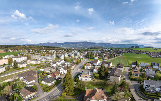 Aerial view of residential houses green meadows and the Jura mountains under a blue sky in Biberist Solothurn Switzerland. Aerial view of residential houses green meadows and the Jura mountains under a blue sky in Biberist Solothurn Switzerland.