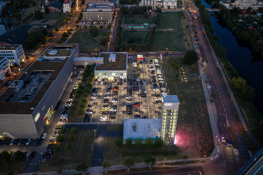 Berlin Germany 07 September 2026 Aerial view of Audi Zentrum Berlin Adlershof featuring the illuminated dealership parking lot filled with cars and the glass car tower at dusk.