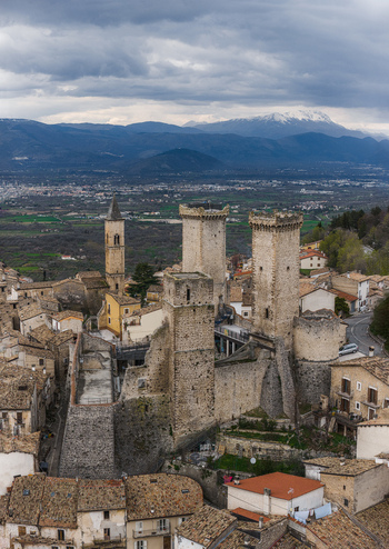Aerial view of the medieval Caldora Castle with its tall stone towers and the historic village surrounded by mountains in Pacentro Abruzzo Italy. Aerial view of the medieval Caldora Castle with its tall stone towers and the historic village surrounded by mountains in Pacentro Abruzzo Italy.