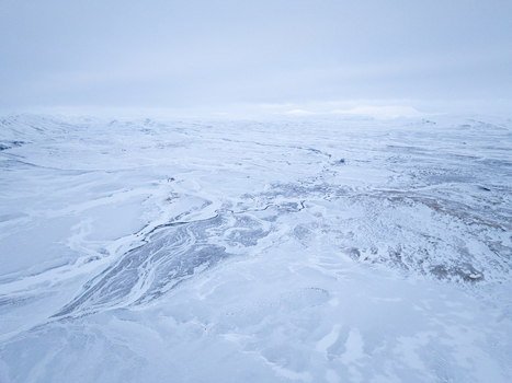 Aerial view of the vast snow covered landscape with winding river patterns and distant mountains in Egilsstadir Mulathing Iceland. Aerial view of the vast snow covered landscape with winding river patterns and distant mountains in Egilsstadir Mulathing Iceland.