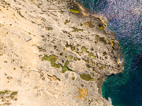 Aerial view of the rugged limestone coastline and natural rock pools at Dwejra Bay with clear turquoise water in Gozo Region Malta. Aerial view of the rugged limestone coastline and natural rock pools at Dwejra Bay with clear turquoise water in Gozo Region Malta.