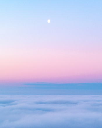 Aerial view of a soft pink and blue twilight sky with a crescent moon above a thick sea of clouds Nuffield Oxfordshire United Kingdom. Aerial view of a soft pink and blue twilight sky with a crescent moon above a thick sea of clouds Nuffield Oxfordshire United Kingdom.