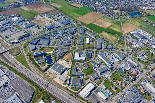 Aerial view of a vibrant industrial area with geometric buildings and roundabouts contrasted by the surrounding patchwork of agricultural fields Sausheim Grand Est France.