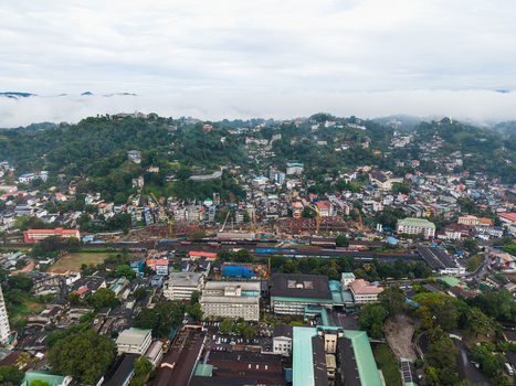 Aerial view of the urban landscape of Kandy with its dense buildings railway tracks and mist covered hills under a cloudy sky Kandy Central Province Sri Lanka. Aerial view of the urban landscape of Kandy with its dense buildings railway tracks and mist covered hills under a cloudy sky Kandy Central Province Sri Lanka.