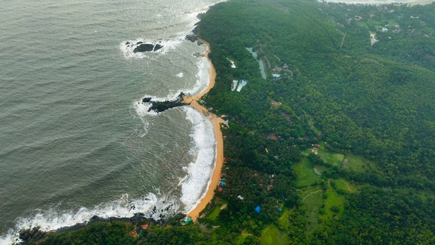 Aerial view of Om Beach Birdview Point with its iconic crescent shaped coastline lush green hills and waves crashing against the rocky shore in Gokarna Karnataka India. Aerial view of Om Beach Birdview Point with its iconic crescent shaped coastline lush green hills and waves crashing against the rocky shore in Gokarna Karnataka India.
