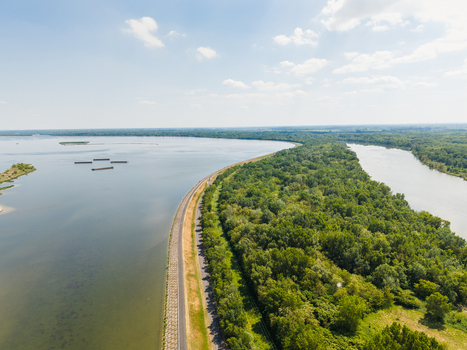 Aerial view of the Danube river and Hrusov reservoir with a paved embankment road and dense green forest under a bright sky Bratislava Bratislava Region Slovakia. Aerial view of the Danube river and Hrusov reservoir with a paved embankment road and dense green forest under a bright sky Bratislava Bratislava Region Slovakia.