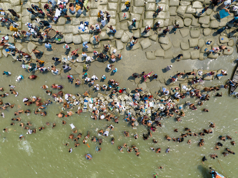 Aerial view of crowds gathering along the riverbank their forms a mosaic against the textured stones and flowing water Charmonai Barisal Division Bangladesh. Aerial view of crowds gathering along the riverbank their forms a mosaic against the textured stones and flowing water Charmonai Barisal Division Bangladesh.