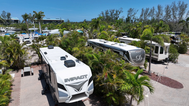 Aerial view of recreational vehicles parked in a lush tropical RV resort with palm trees and paved sites in Cortez Florida United States.