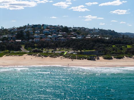 Aerial view of Northern Beaches with sandy coastline turquoise ocean waves and residential houses on the hillside in Northern Beaches Council New South Wales Australia.