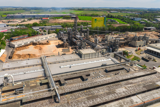 Aerial view of a large industrial wood processing plant with complex piping systems silos and storage areas Jihlava Vysocina Region Czechia.