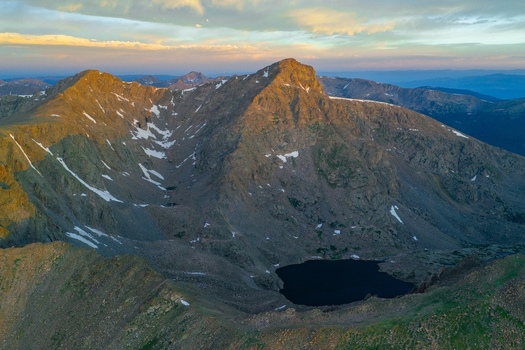 Aerial view of Mount of the Holy Cross in the Sawatch Range featuring rugged mountain peaks patches of snow and a dark alpine lake in Vail Colorado United States. Aerial view of Mount of the Holy Cross in the Sawatch Range featuring rugged mountain peaks patches of snow and a dark alpine lake in Vail Colorado United States.