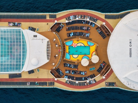 Aerial view of a cruise ship deck featuring a swimming pool with colorful patterns rows of lounge chairs and a glass covered solarium area in Cannes Provence Alpes Cote d Azur France. Aerial view of a cruise ship deck featuring a swimming pool with colorful patterns rows of lounge chairs and a glass covered solarium area in Cannes Provence Alpes Cote d Azur France.