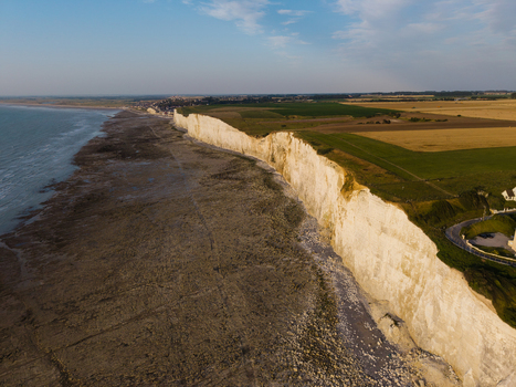 Aerial view of the chalk cliffs at Beach of the Bois de Cise with the coastline meeting the sea and agricultural fields in Ault Hauts de France France.