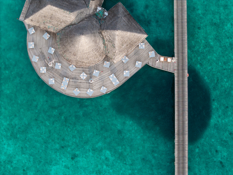Aerial view of a luxurious overwater bungalow resort with thatched roofs casting shadows on turquoise waters Hoarafushi Thiladhunmathee Uthuruburi Maldives. Aerial view of a luxurious overwater bungalow resort with thatched roofs casting shadows on turquoise waters Hoarafushi Thiladhunmathee Uthuruburi Maldives.