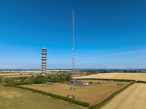 Aerial view of the Morborne Hill Transmitter with its tall telecommunications mast and concrete tower set in agricultural fields under a clear blue sky in Morborne England United Kingdom. Aerial view of the Morborne Hill Transmitter with its tall telecommunications mast and concrete tower set in agricultural fields under a clear blue sky in Morborne England United Kingdom.