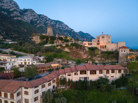 Aerial view of the historic Kruje Castle with its stone watchtower and Skanderbeg Museum overlooking red tiled rooftops and rugged mountains at dusk in Kruje Durres County Albania.