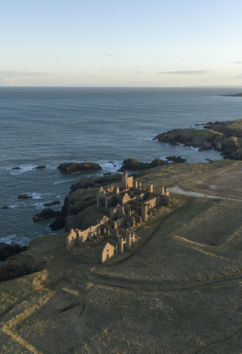 Aerial view of the historic Slains Castle ruins perched on rugged cliffs overlooking the North Sea in Cruden Bay Scotland United Kingdom. Aerial view of the historic Slains Castle ruins perched on rugged cliffs overlooking the North Sea in Cruden Bay Scotland United Kingdom.