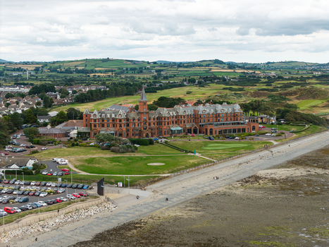 Aerial view of the historic Slieve Donard Hotel surrounded by lush green golf courses and coastal scenery in Newcastle Northern Ireland United Kingdom. Aerial view of the historic Slieve Donard Hotel surrounded by lush green golf courses and coastal scenery in Newcastle Northern Ireland United Kingdom.